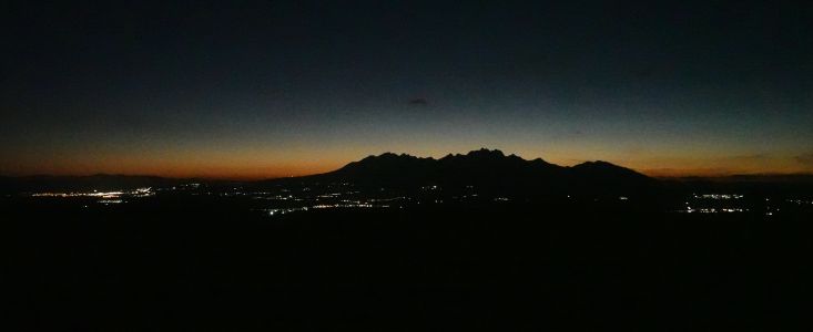 Noční Vysoké Tatry, vlevo svítí Poprad, uprostřed Kežmarok.